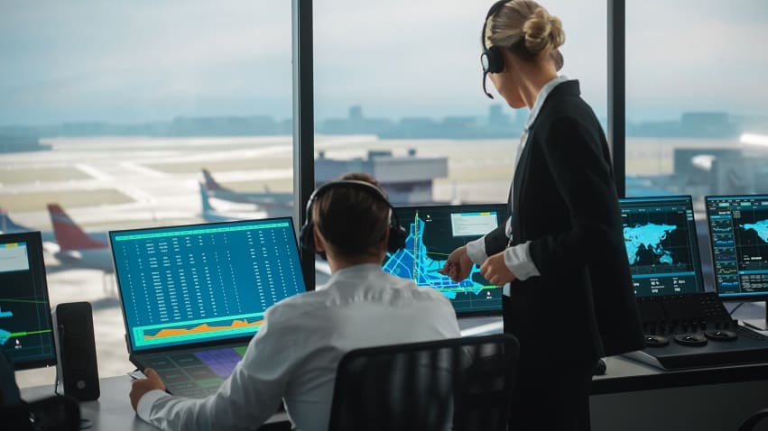 Weibliche und männliche Fluglotsen mit Headsets Sprechen im Airport Tower